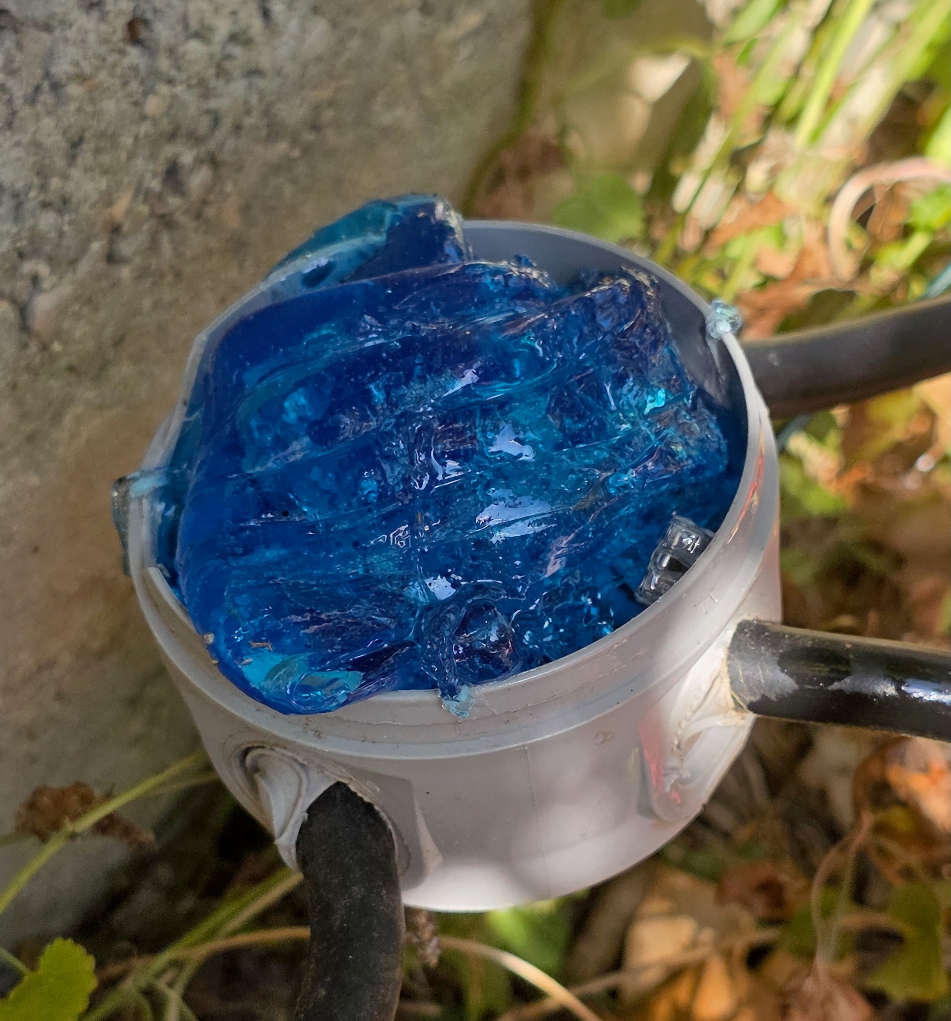 Scatola di derivazione rotonda grigia riempita di Magic Gel blu vista dall’alto, morsetti completamente immersi