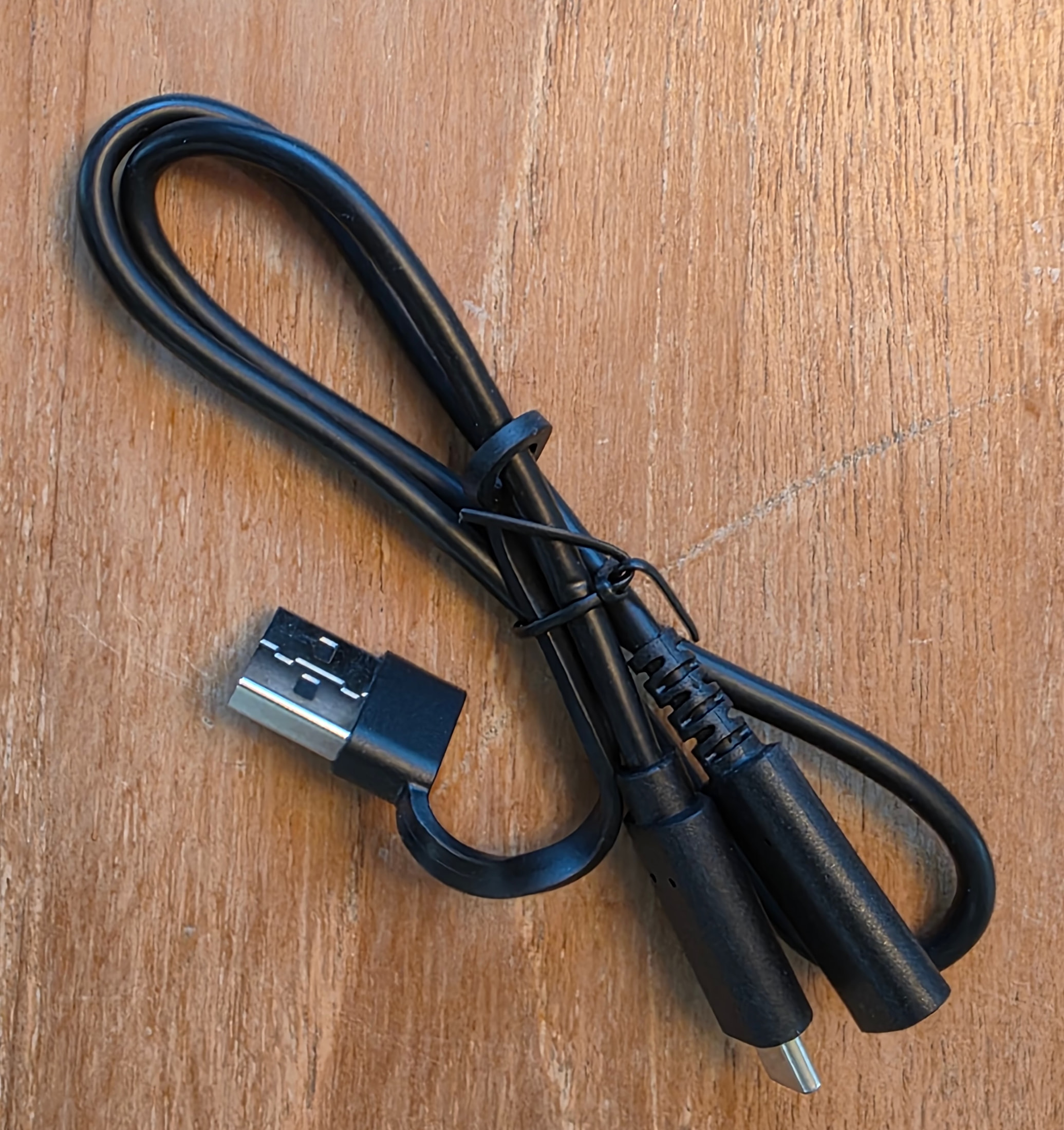 Cable USB negro incluido con la Thermal Master P3, fotografiado sobre una mesa de madera