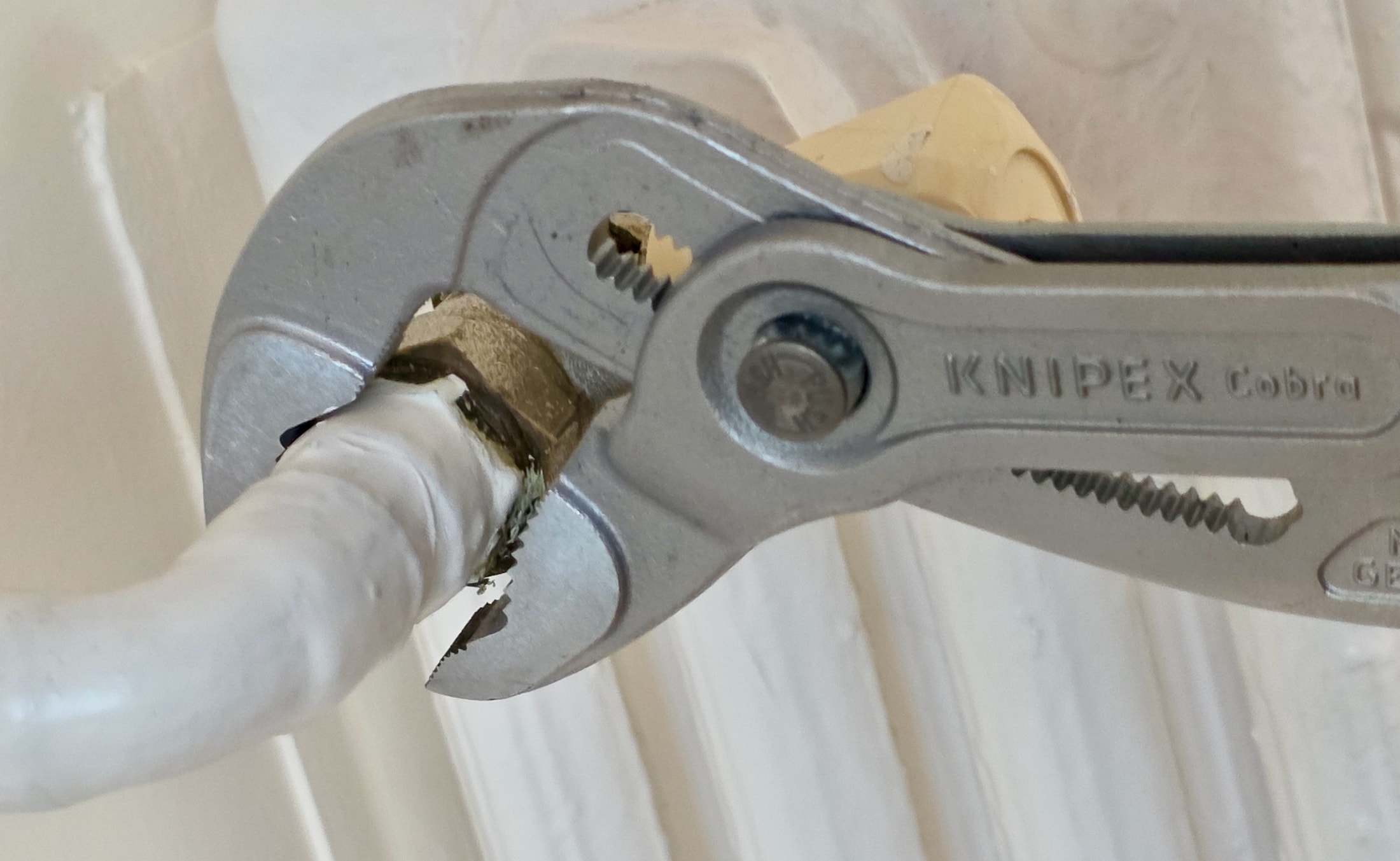 Primer plano de la mordaza de la pinza Knipex Cobra 87 03 300, agarrando una tuerca de radiador