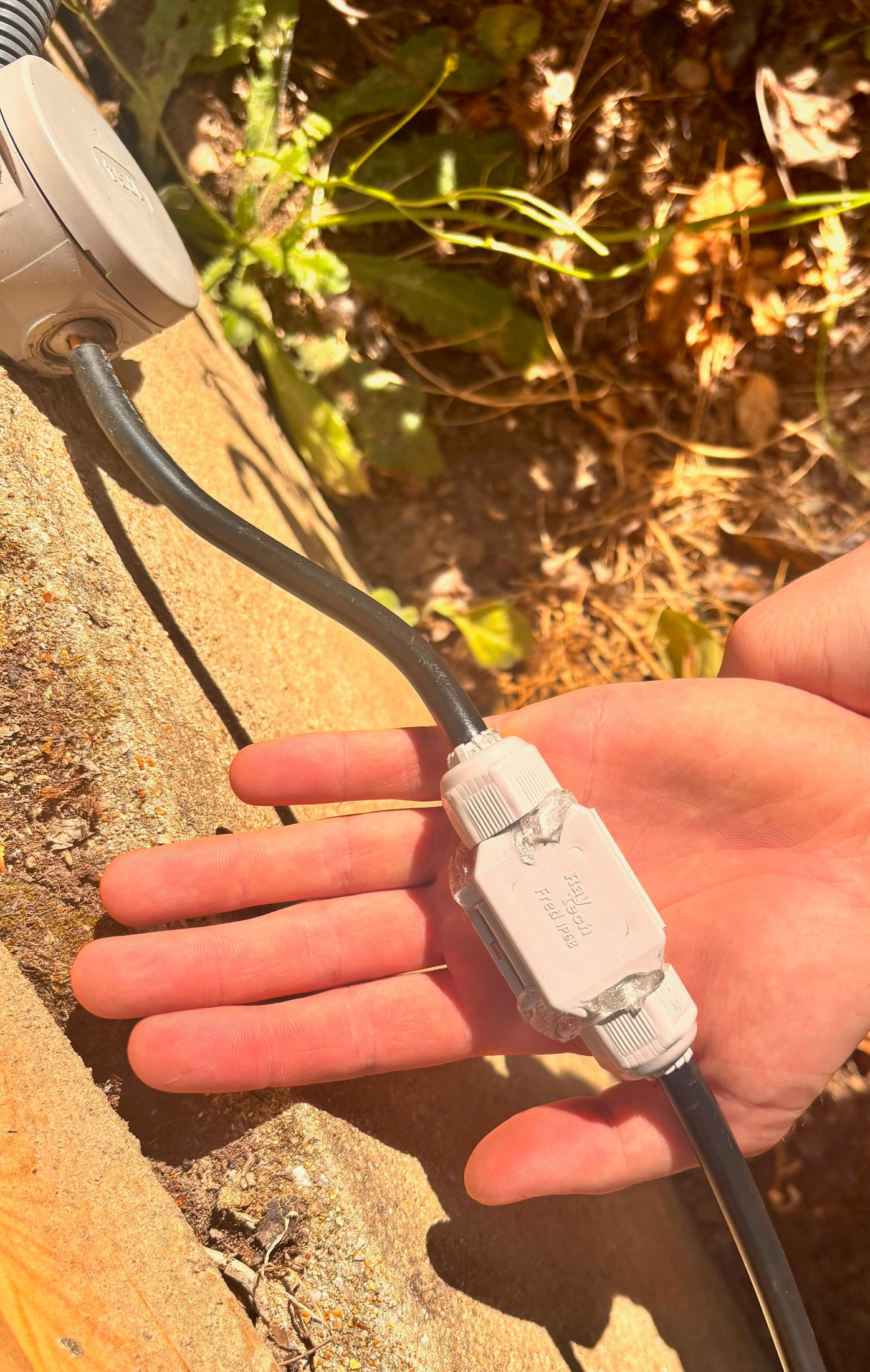 Raytech Fred IP68-Steckverbinder in der Hand gehalten, geschlossen mit einem innen angeschlossenen Domino, das Gel quillt leicht über die Ränder