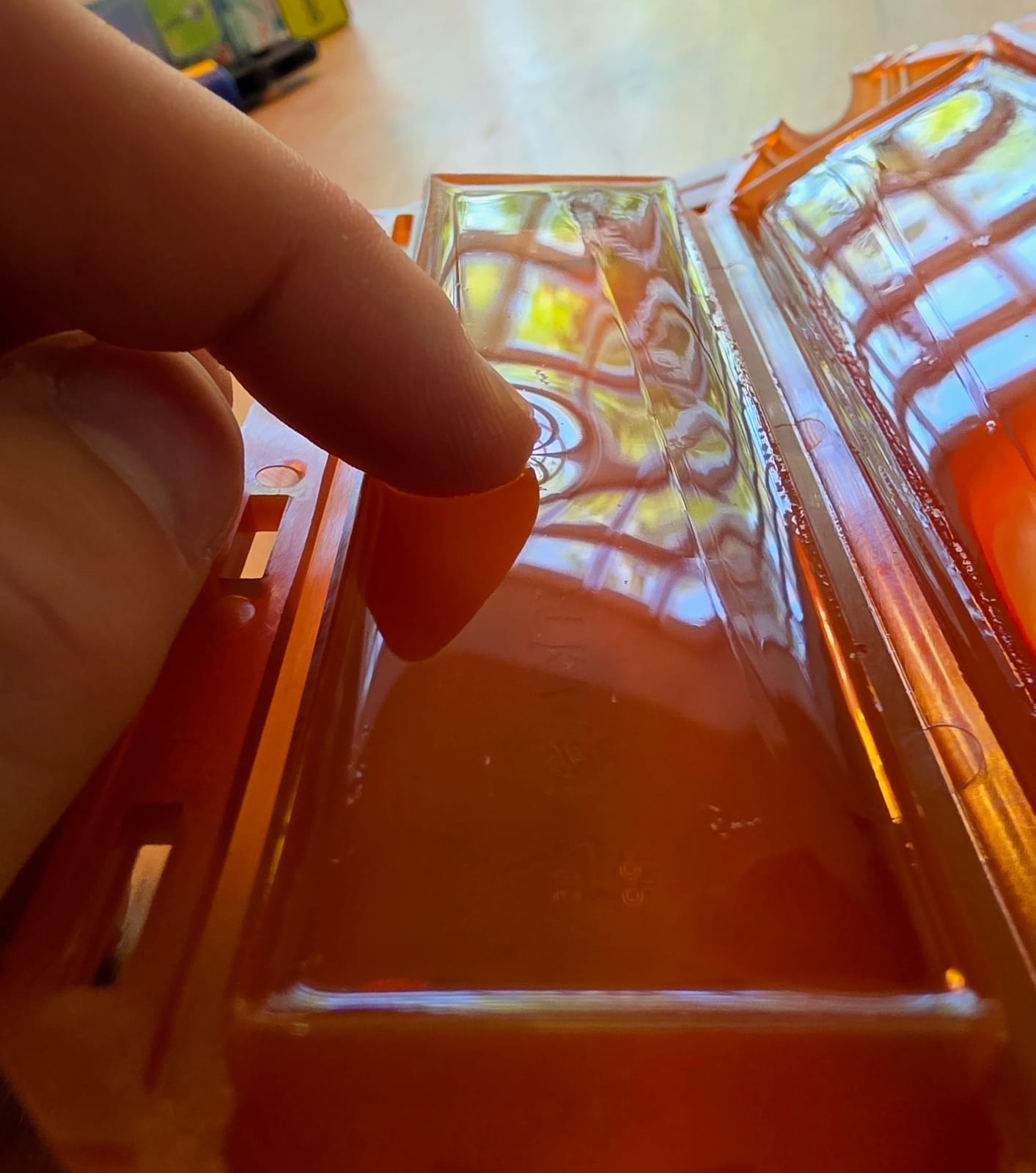 Dito che tocca la resina gel all'interno di un guscio arancione Ready Cast, primo piano