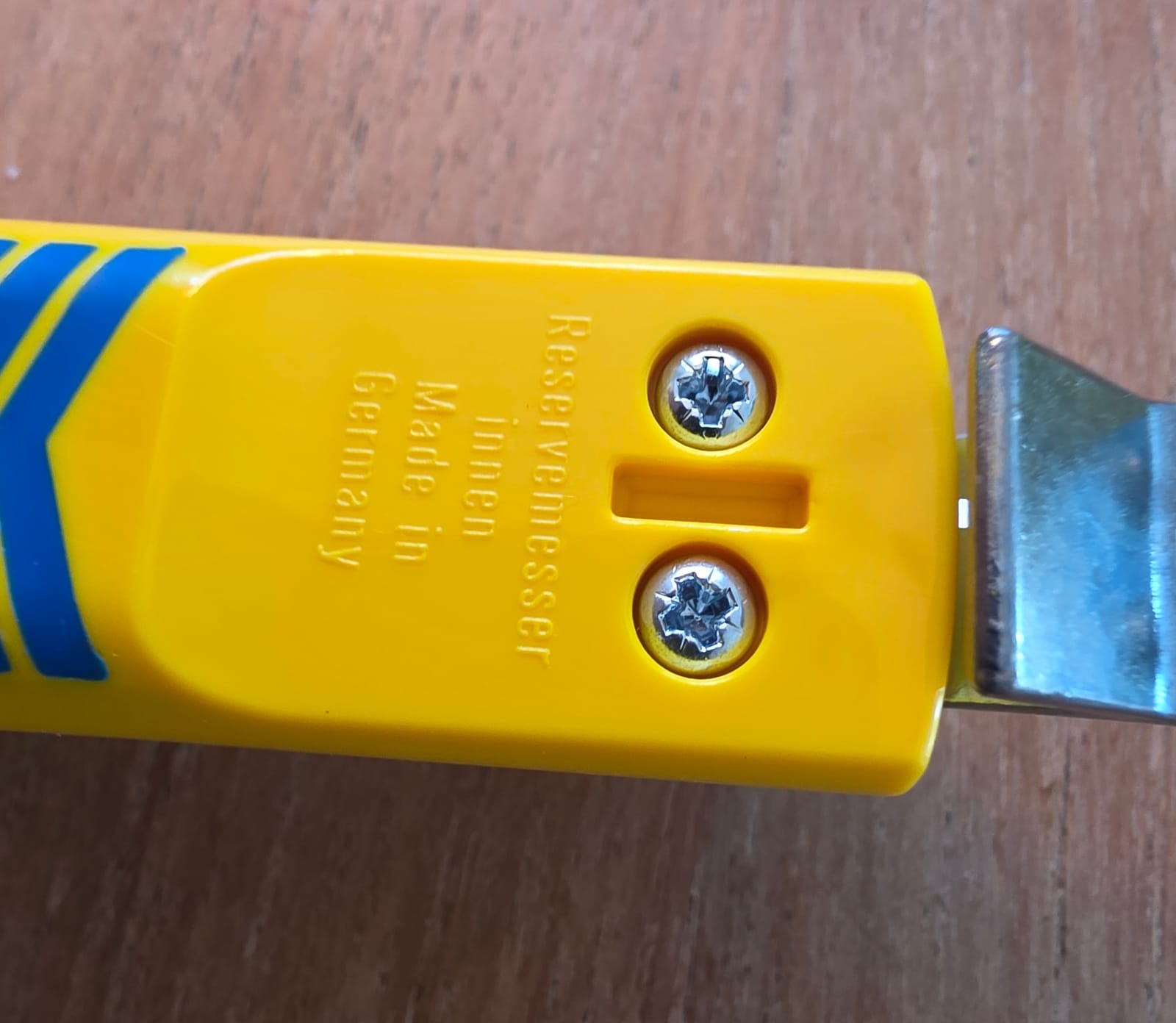 Retro dell’impugnatura gialla dello spelacavi Jokari con la scritta Reservemesser innen e due viti