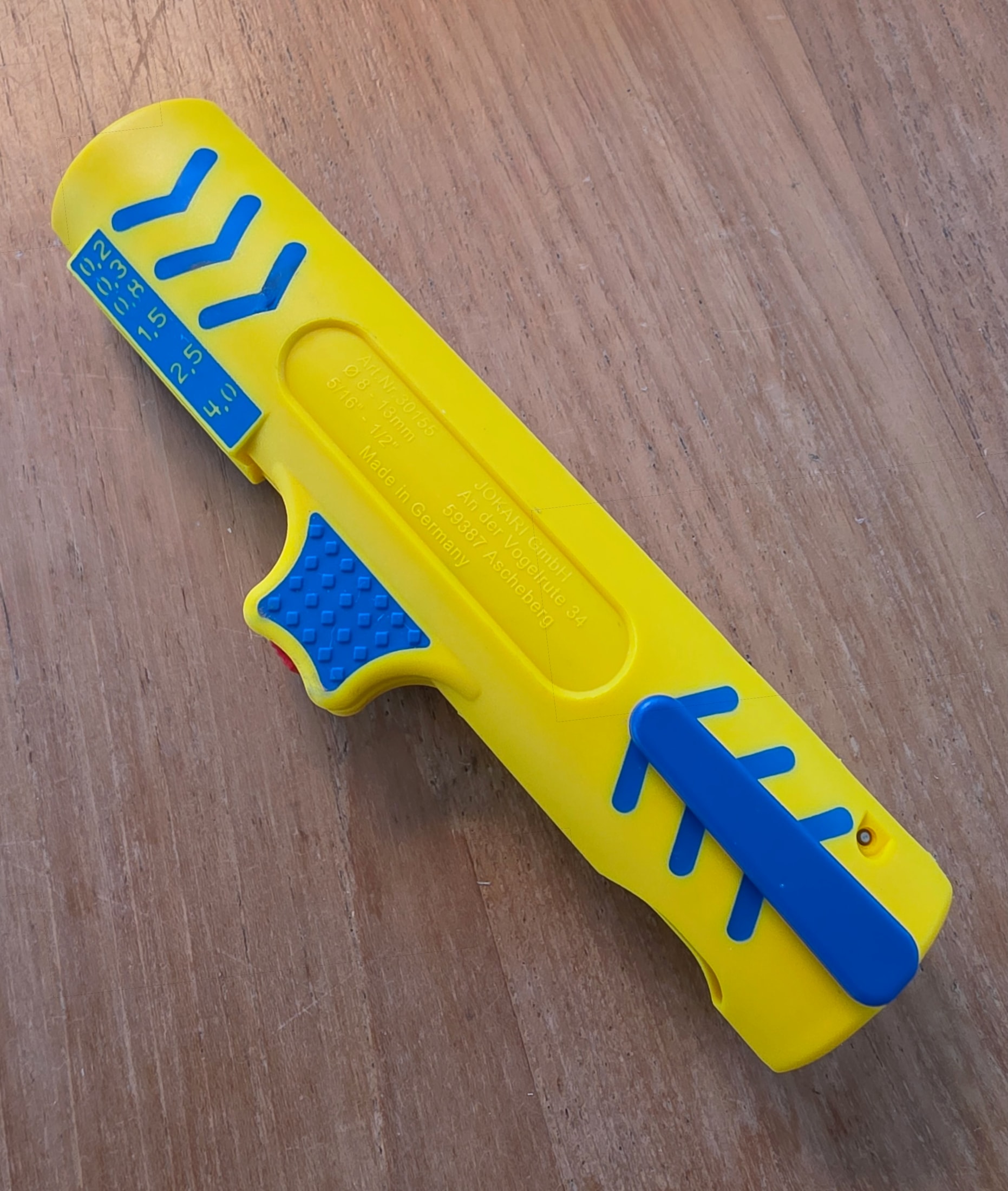 Back of the yellow and blue Jokari Secura No. 15 wire stripper resting on a workbench, printed reference visible
