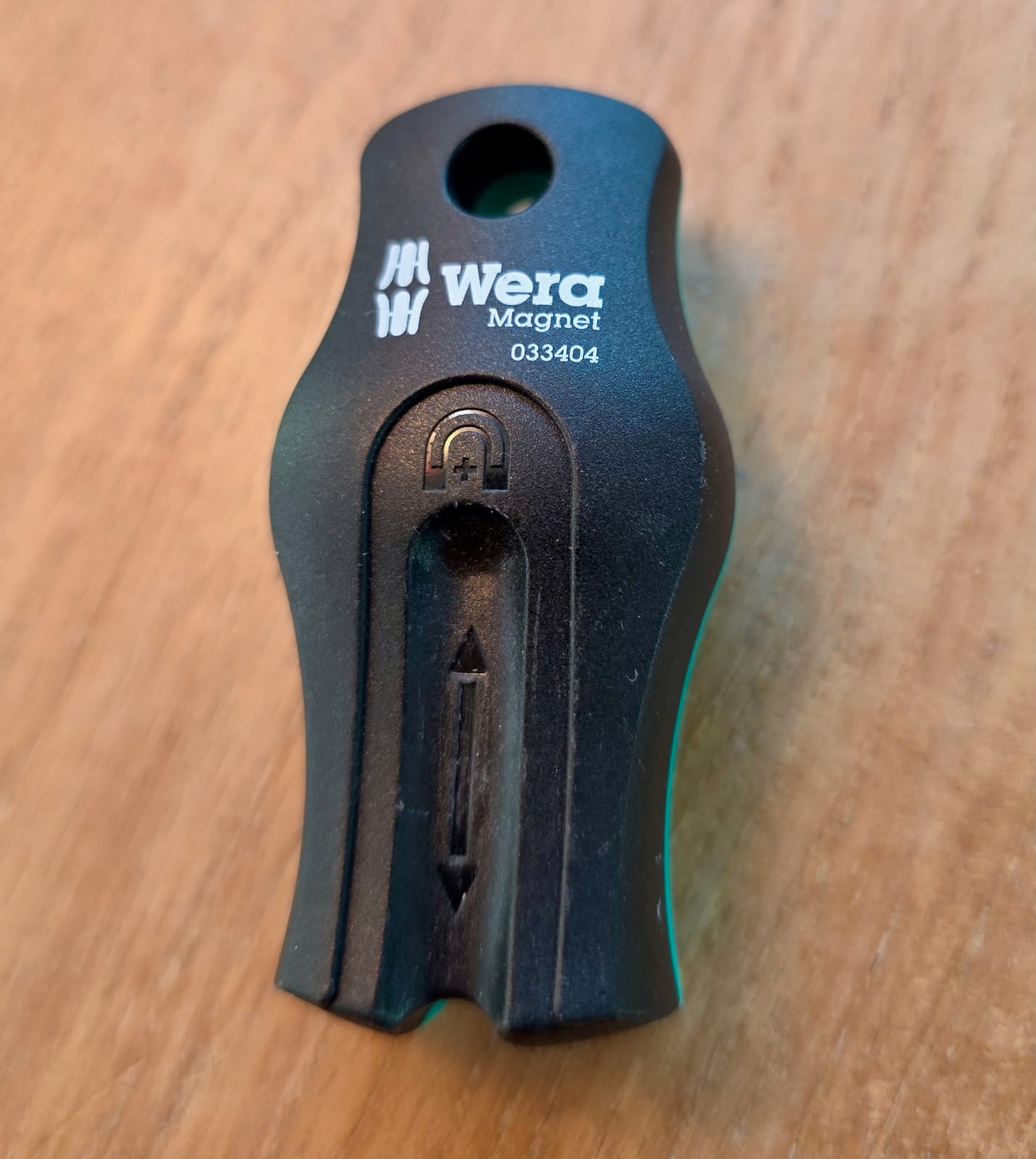Magnetizador y desmagnetizador Wera negro con detalles verdes sobre una superficie de madera