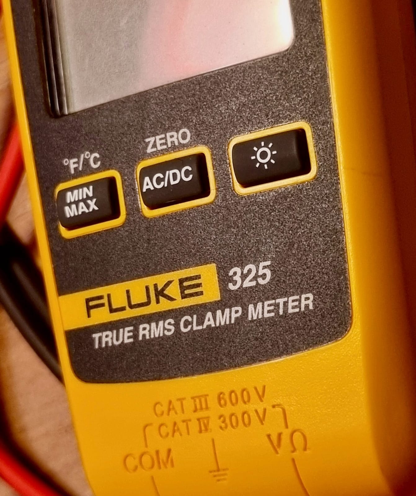 Primer plano de la cara inferior de una pinza amperimétrica Fluke 325 con el marcado CAT III 600 V y CAT IV 300 V grabado cerca de las bornas de medida