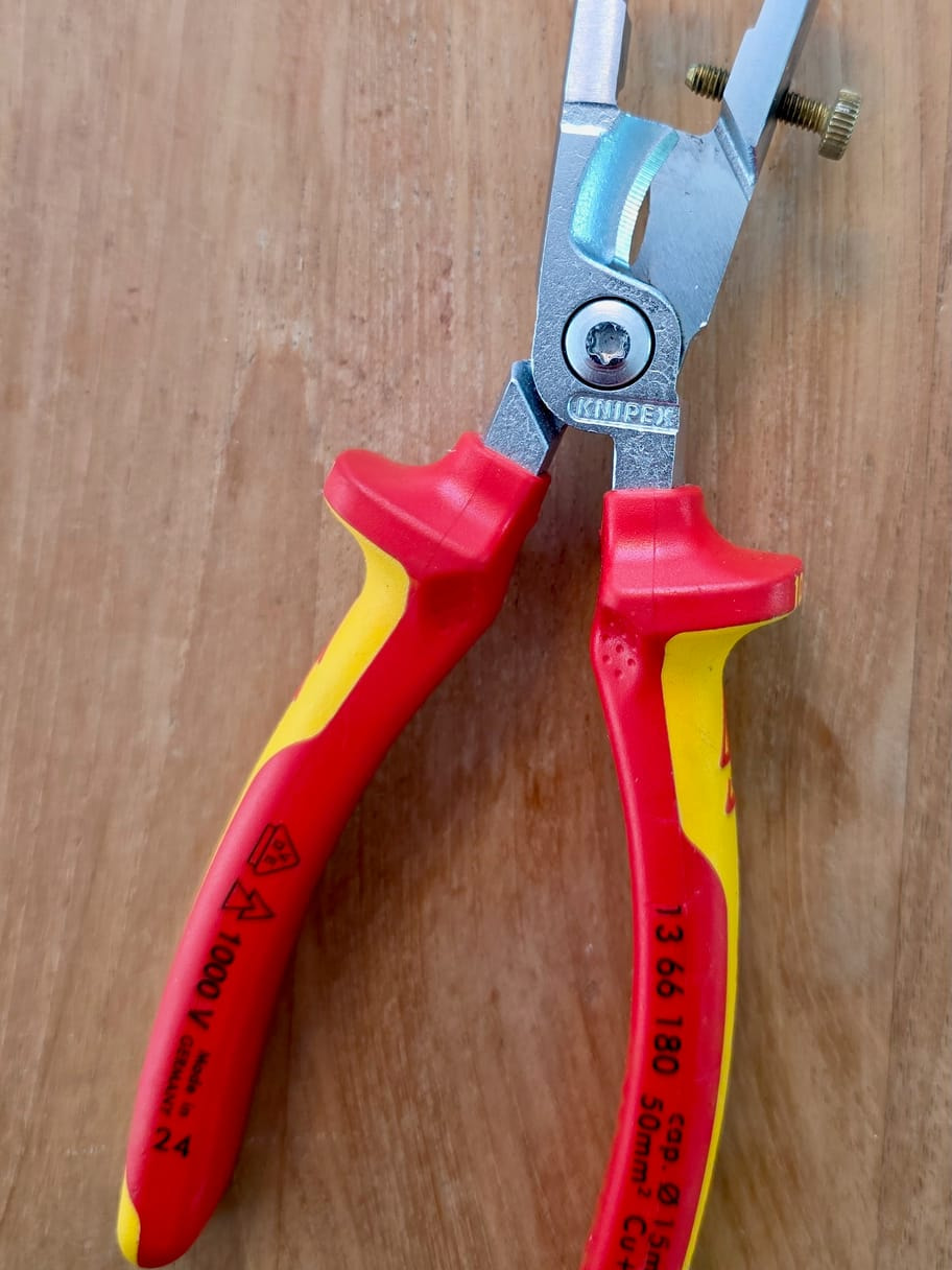 Pinza spellafili Knipex 13 66 180 VDE posata su un tavolo con il suo telaio guida