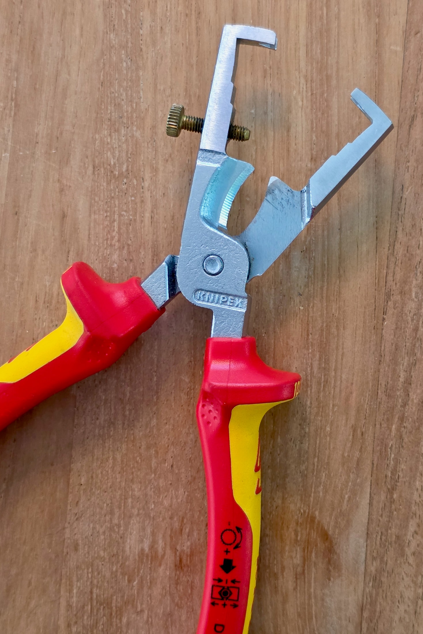 Knipex 13 66 180 VDE wire stripping pliers on a table, open jaw and adjustment screw visible