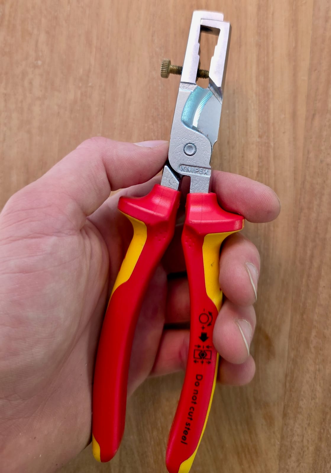 Alicate pelacables Knipex 13 66 180 VDE sujeto con la mano, mangos amarillo y rojo
