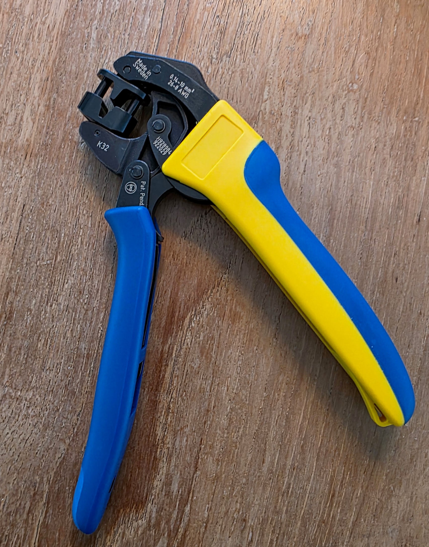 Pinza de crimpar Klauke K32 TWIST-it completa sobre una superficie de madera, grabados del modelo, del rango de crimpado y de la fabricación visibles