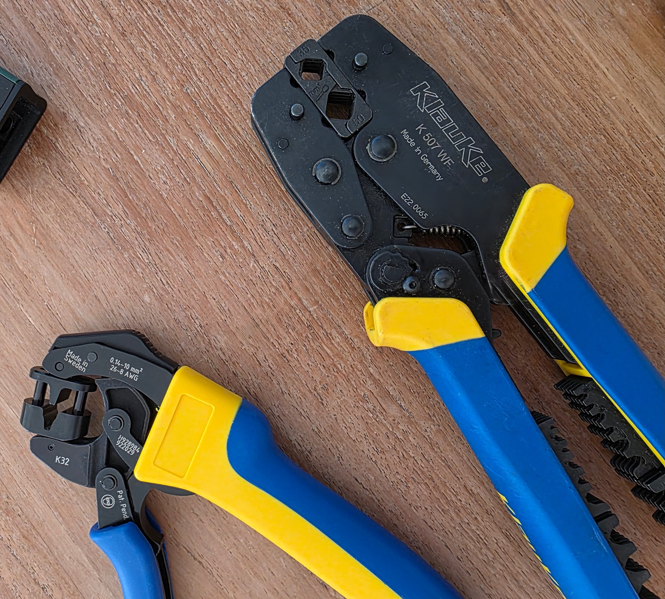 Dos pinzas de crimpar Klauke K 507 WF y K 32 colocadas sobre un banco de trabajo de madera, mangos azules y amarillos, grabados Made in Germany y Made in Sweden en las mordazas