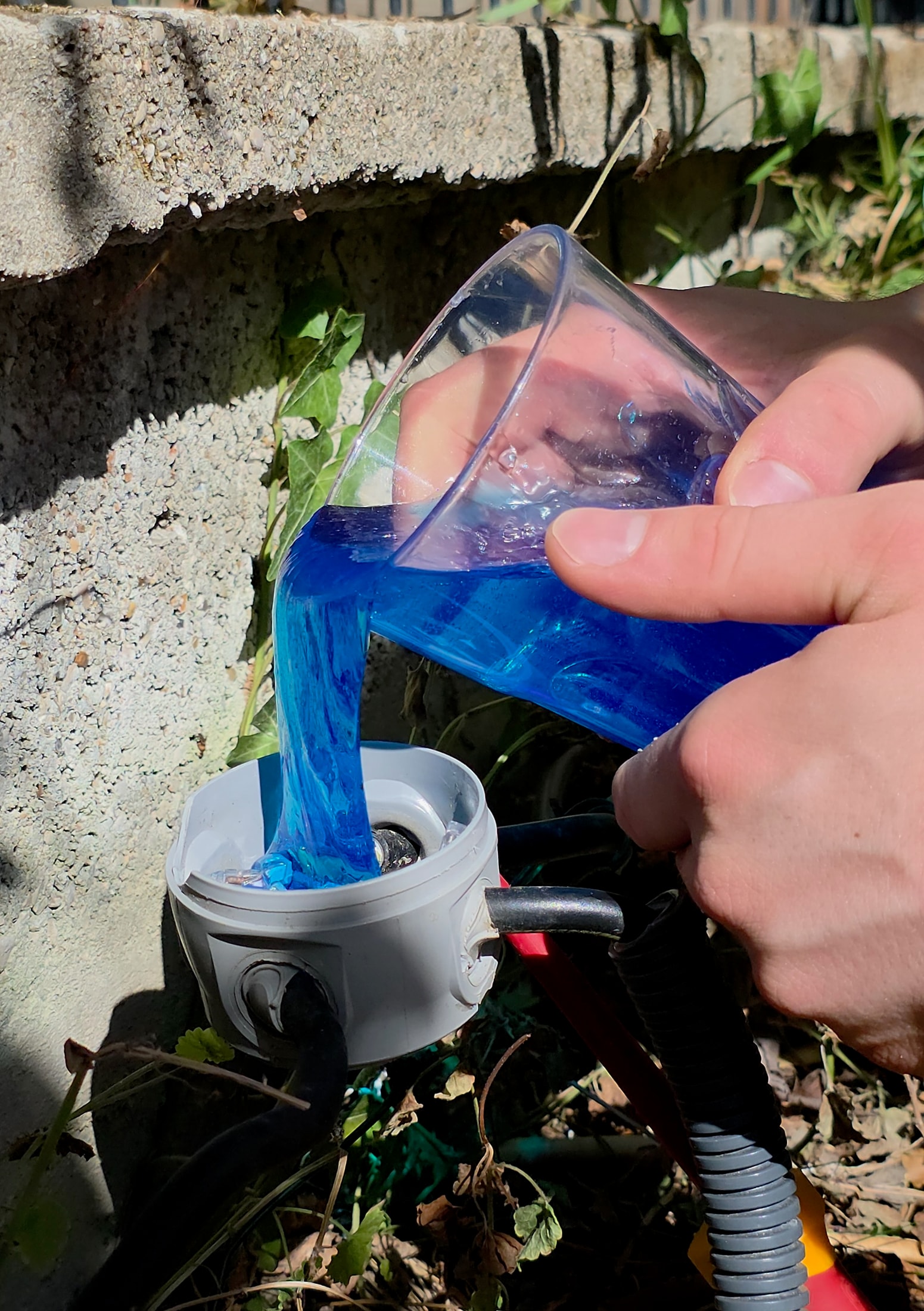 Magic Gel isolante blu versato da un bicchiere in una scatola di derivazione rotonda grigia