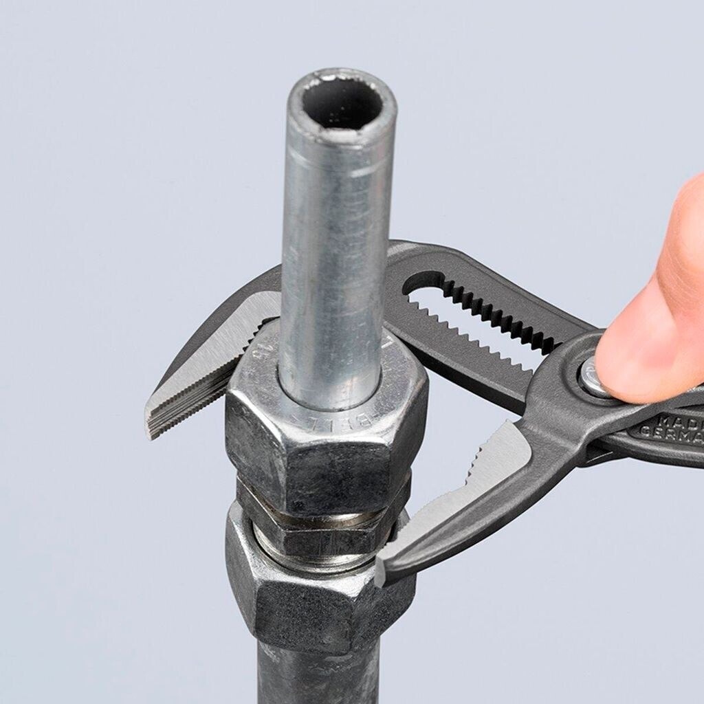 Una pinza multiusos KNIPEX Cobra ES aprieta una tuerca hexagonal sobre un tubo metálico mientras un dedo aprieta el botón de ajuste.
