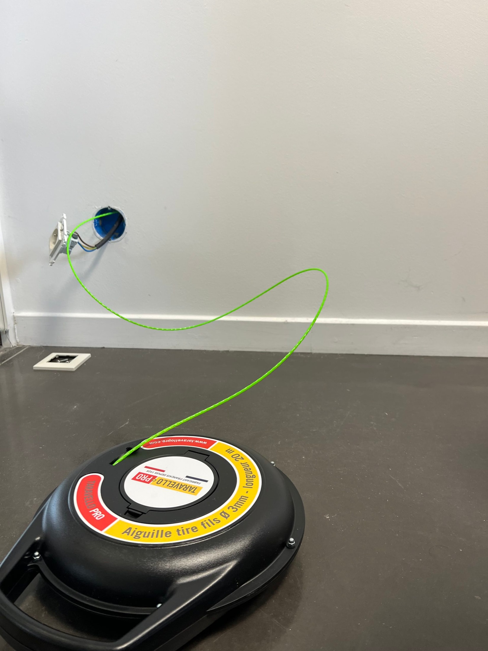 Taravello Pro spool on the floor with the green wire run out to a flush-mounting box