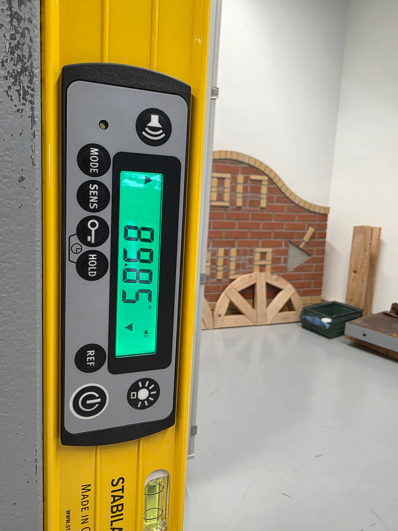 Close-up of the digital display of a STABILA electronic level showing 89.85 degrees, with the MODE, SENS, HOLD and REF buttons visible